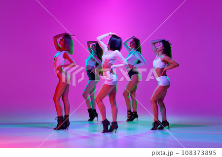 Beautiful, elegant, attractive women dancing high heel dance over pink studio background in neon light 108373895