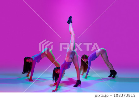 Beautiful, artistic, elegant women with slim bodies dancing high heel dance over pink studio background in neon light 108373915