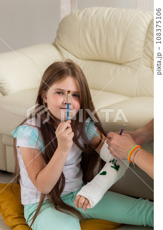Broken arm a child. Mom and daughter paint on bandage Broken arm a child. Mom and daughter paint on bandage 108375106