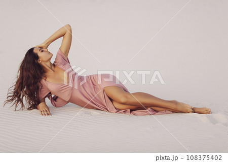 Laying in Desert Fashion Woman Model in Evening Pink Dress  108375402