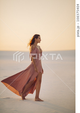 Walking in Desert Fashionable Woman Model in Evening Pink Dress  108375404