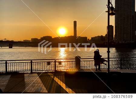 夕陽を背景に子どもを抱き上げるお母さん 108376589