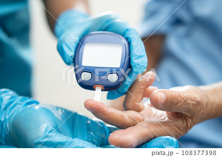 Doctor check diabetes from finger blood sugar level with finger lancet. 108377398