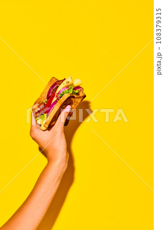 Woman holding delicious sandwich with grilled bread, ham, lettuce, cheese, tomato, onion and avocado over yellow background. Cooking, taste. Poster Woman holding delicious sandwich with grilled bread, ham, lettuce, cheese, tomato, onion and avocado over yellow background. Cooking, taste. Poster 108379315