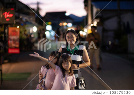 Happy family, mother and her children pose for the camera at Pai Night Walking Street, Mae Hong Son, Thailand Happy family, mother and her children pose for the camera at Pai Night Walking Street, Mae Hong Son, Thailand 108379530