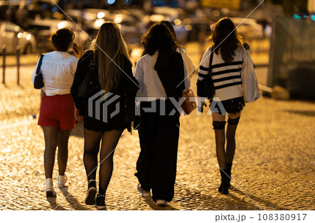 A group of young woman walking together during the night - view from behind A group of young woman walking together during the night - view from behind 108380917