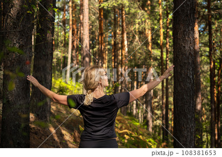 Beautiful woman walking through the forest, idea of restoring health and relaxation, forest baths Beautiful woman walking through the forest, idea of restoring health and relaxation, forest baths 108381653