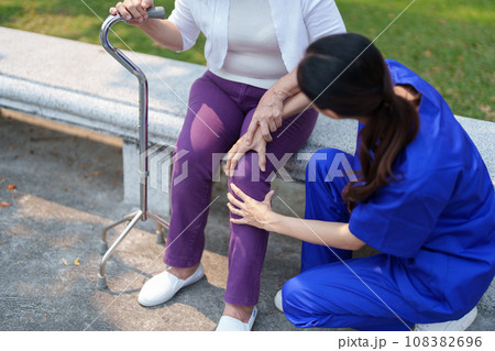 Patient care, female care, young Asian women are taking care of the elderly, providing crutches and walking for patients, and exercising their legs and knees in the park parks Patient care, female care, young Asian women are taking care of the elderly, providing crutches and walking for patients, and exercising their legs and knees in the park parks 108382696