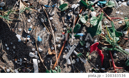 A high-angle view of sand and vegetation intermixed with microplastics. The pressing problem is the role microplastics play in heating up our planet. 108383536