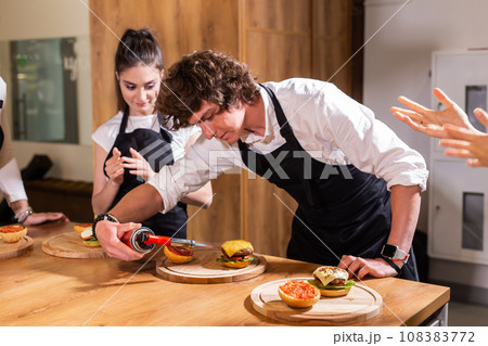Preparing delicious burgers. Chef cooking meat burgers with beef, cheese and vegetables. Close-up Preparing delicious burgers. Chef cooking meat burgers with beef, cheese and vegetables. Close-up 108383772