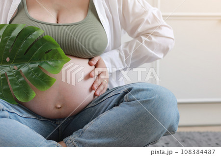 Close-up of torso of young pregnant model applying moisturizer on her belly to avoid stretch marks. Future mom. Pregnancy skincare concept 108384487