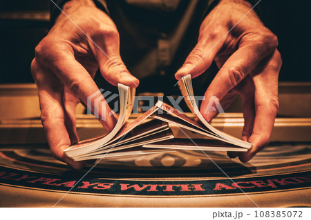 Dealer or croupier shuffles poker cards in a casino on the background of a table, chips. Concept of poker game, game business. Playing for money, a big win, a jackpot, gambling, a desire to get rich. Dealer or croupier shuffles poker cards in a casino on the background of a table, chips. Concept of poker game, game business. Playing for money, a big win, a jackpot, gambling, a desire to get rich. 108385072