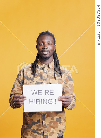 Company entrepreneur holding hiring application sign at camera, advertising corporate job offer and business career opportunity. African american man preparing interview for recruiting applicant. Company entrepreneur holding hiring application sign at camera, advertising corporate job offer and business career opportunity. African american man preparing interview for recruiting applicant. 108387534