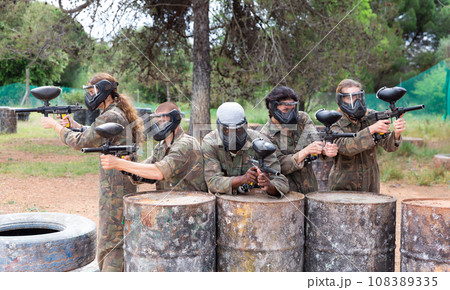 Group of paintball players aiming and shooting with guns Group of paintball players aiming and shooting with guns 108389335