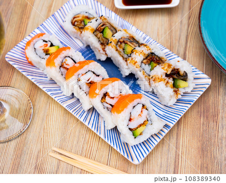 Appetizing sushi roll uramaki - unagi avocado roll with cooked prawns, avocado, onion and salmon 108389340