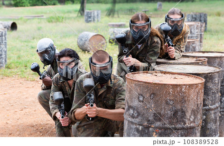 Group of paintball players aiming and shooting with guns Group of paintball players aiming and shooting with guns 108389528