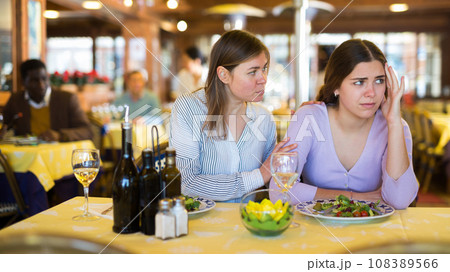 Woman comforting upset female friend during dinner in restaurant Woman comforting upset female friend during dinner in restaurant 108389566