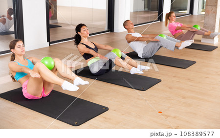 Sports people perform an exercise with a ball Sports people perform an exercise with a ball 108389577