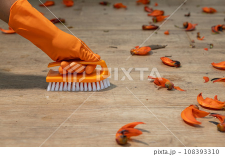 Worker wearing orange rubber gloves is scrub cleaning dirty filthy patio floor. Worker wearing orange rubber gloves is scrub cleaning dirty filthy patio floor. 108393310