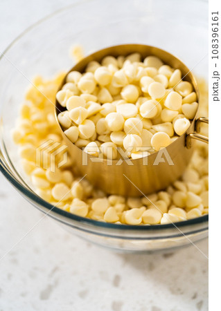 White chocolate chips in a glass mixing bowl. 108396161