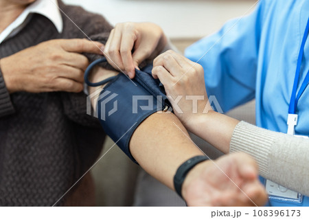 Nurses or caregivers take care of elderly by helping to check their blood pressure Nurses or caregivers take care of elderly by helping to check their blood pressure 108396173