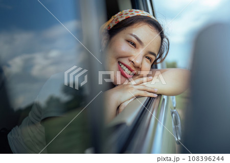 Smiling female driving vehicle on the road on a bright day. Sticking her head out the windshield 108396244