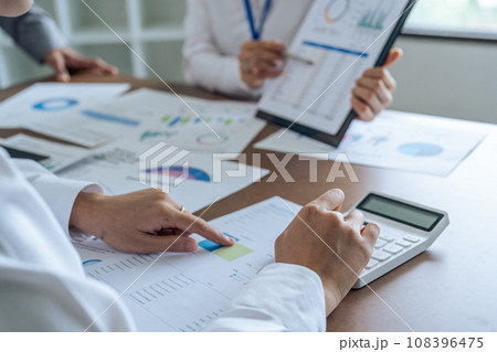 Businesswoman using a calculator to calculate numbers on a company's financial documents, she is analyzing historical financial data to plan how to grow the company. Financial concept Businesswoman using a calculator to calculate numbers on a company's financial documents, she is analyzing historical financial data to plan how to grow the company. Financial concept 108396475