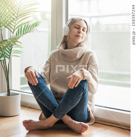Young caucasian woman relaxes at home with music Young caucasian woman relaxes at home with music 108397244