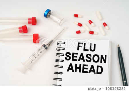On the table are pills, injections, a syringe and a notepad with the inscription - flu season ahead 108398282