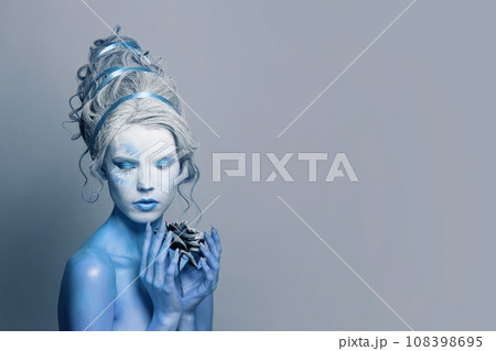Beautiful model woman with blue skin, stage makeup and hairstyle with black rose flower  108398695