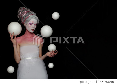 Gorgeous woman witch fairy with pink and white skin holding white planet spheres on black background 108398696