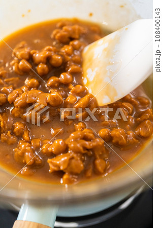 Melting chocolate chips and other ingredients in a glass mixing bowl over boiling water to prepare caramel fudge. Melting chocolate chips and other ingredients in a glass mixing bowl over boiling water to prepare caramel fudge. 108400143