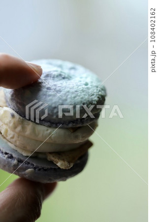 水色のクリームチーズトゥンカロンを持つ手 水色のクリームチーズトゥンカロンを持つ手 108402162