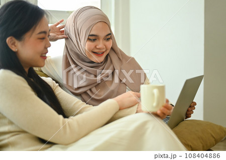 Happy young Muslim woman watching video or surfing internet laptop with her best friend 108404886