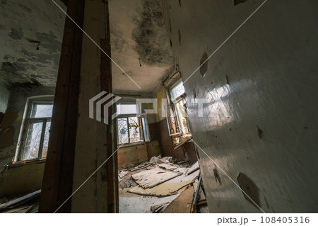 From above interior of shabby abandoned room with peeling painted walls wooden column supporting beam while rubbish garbage of destroyed rubble From above interior of shabby abandoned room with peeling painted walls wooden column supporting beam while rubbish garbage of destroyed rubble 108405316