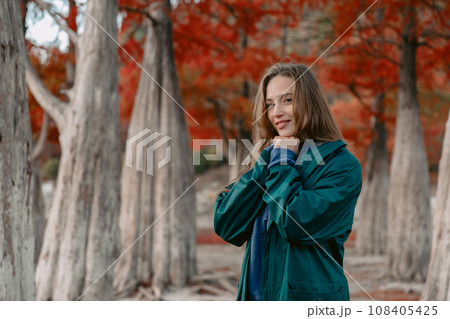 Attractive woman in the park and looking at the camera. People in autumnal forest. Attractive woman in the park and looking at the camera. People in autumnal forest. 108405425