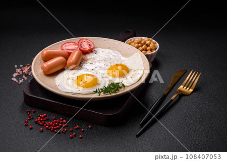 Fried chicken eggs, sausages, cherry tomatoes, chickpeas, spices, salt and herbs 108407053