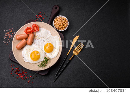 Fried chicken eggs, sausages, cherry tomatoes, chickpeas, spices, salt and herbs 108407054