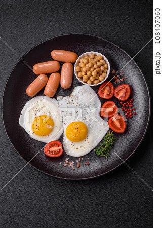 Fried chicken eggs, sausages, cherry tomatoes, chickpeas, spices, salt and herbs 108407060