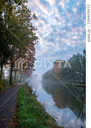 Autumnal Serenity: Canal Amidst Fall Foliage Under Cloud-Kissed Skies 108408415