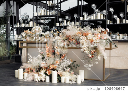 Side view glamour table against mirrored wall with floating candles in vases. Luxury event decor in expensive tones. Side view glamour table against mirrored wall with floating candles in vases. Luxury event decor in expensive tones. 108408647