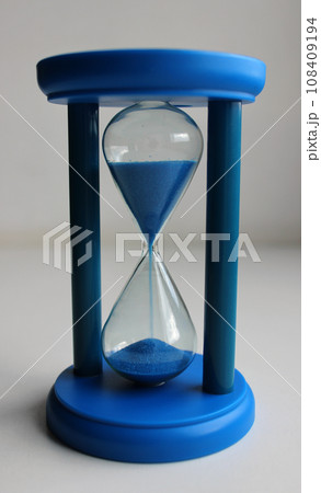 Plastic body of glass timeglass with blue sand pouring inside  108409194