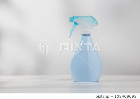 Blue spray bottle on white wooden table. 108409698