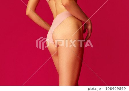 Back view of cropped perfect body shape female body, buttocks, legs in against red studio background. Concept of dieting. Back view of cropped perfect body shape female body, buttocks, legs in against red studio background. Concept of dieting. 108409849