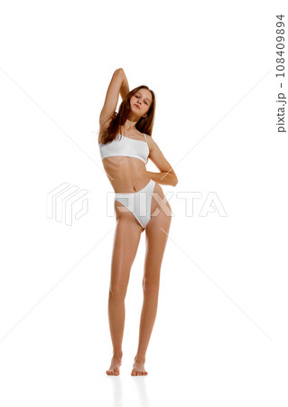 Young beautiful fit woman with long hair posing in white lingerie showing her ideal athlete forms isolated studio background. 108409894
