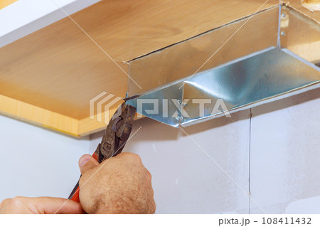 As worker is installing kitchen hood, he places in kitchen cabinet 108411432