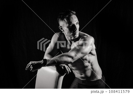 Confident, attractive shirtless muscular young man topless in studio Confident, attractive shirtless muscular young man topless in studio 108411579