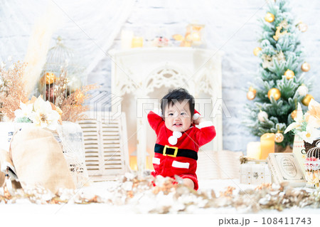 サンタの服を着てクリスマスツリーと一緒に楽しそうにはしゃぐ1歳の笑顔の赤ちゃん サンタの服を着てクリスマスツリーと一緒に楽しそうにはしゃぐ1歳の笑顔の赤ちゃん 108411743