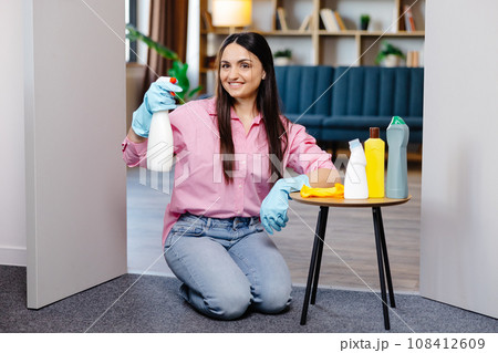 Young woman sitting near the table with cleaning products at home. Young woman sitting near the table with cleaning products at home. 108412609