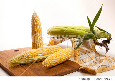 Cutting board with three cobs sweet corn on white wooden background.. 108414931